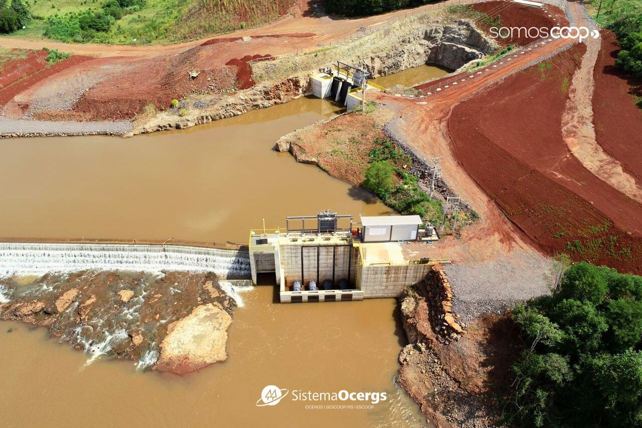 Ceriluz Vista aérea da PCH Linha Onze, da Ceriluz, em Coronel Barros, com barragem, vertedouro e estruturas de geração de energia integradas à paisagem natural e ao solo avermelhado da região.